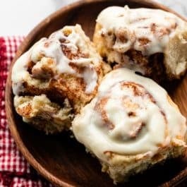 3 cinnamon rolls on wooden plate.