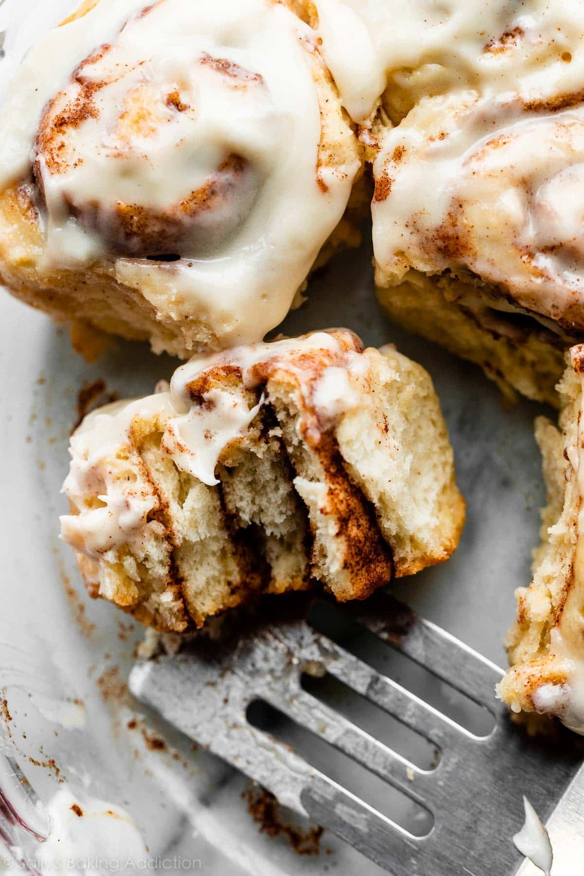 cinnamon roll in glass dish with bite taken out.