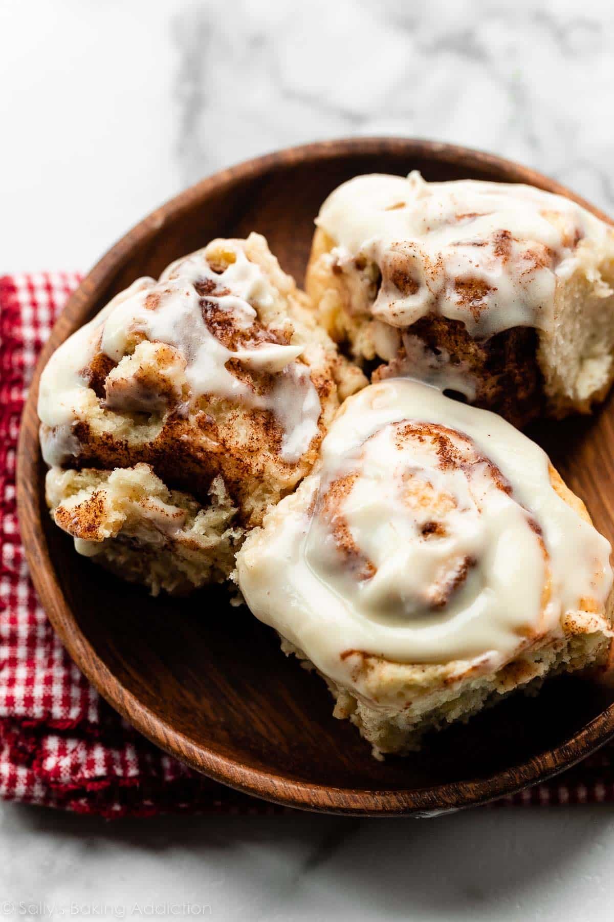 3 cinnamon rolls on wooden plate.