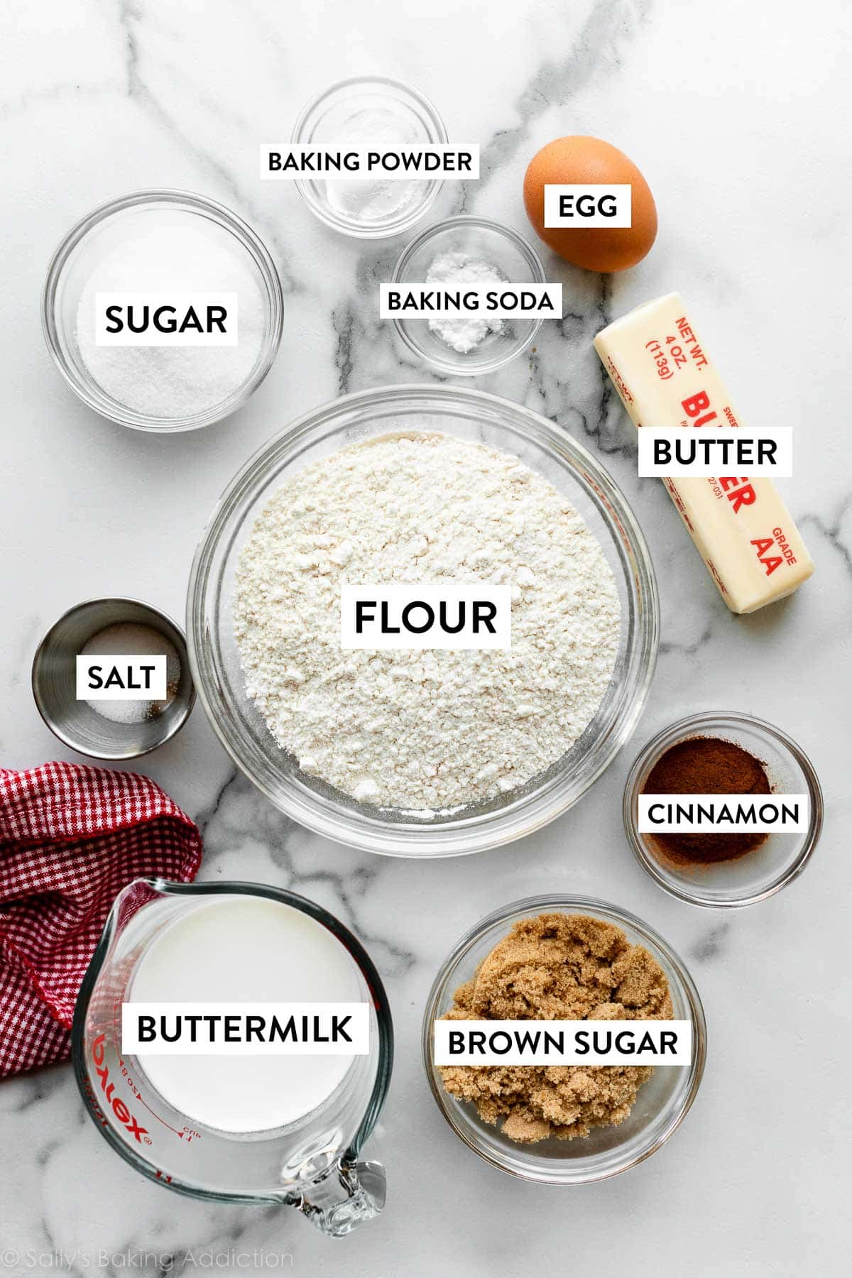 flour, butter, egg, baking powder, sugar, and other ingredients on marble counter.