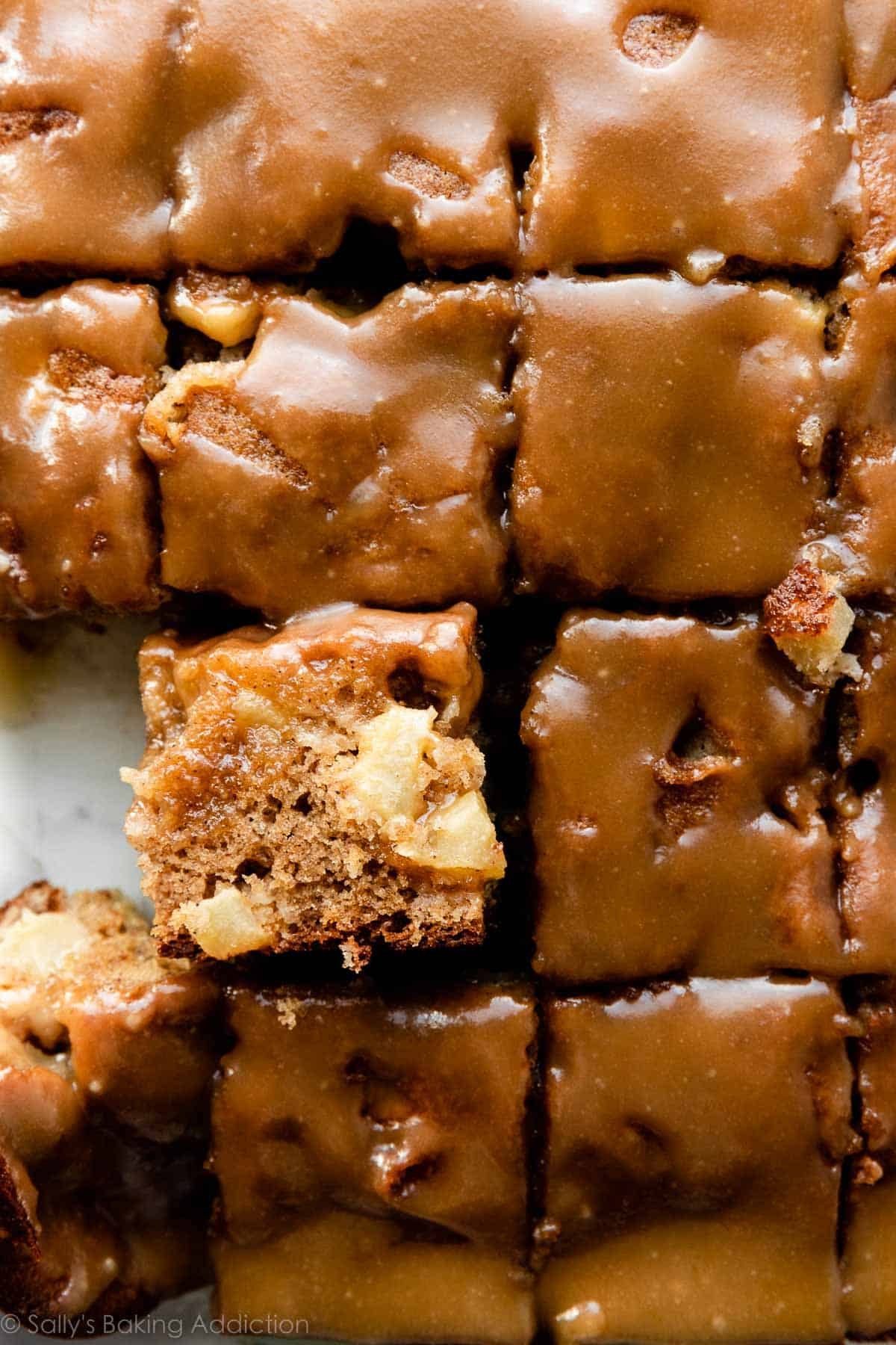 fresh apple cake cut into slices with brown sugar glaze on top.