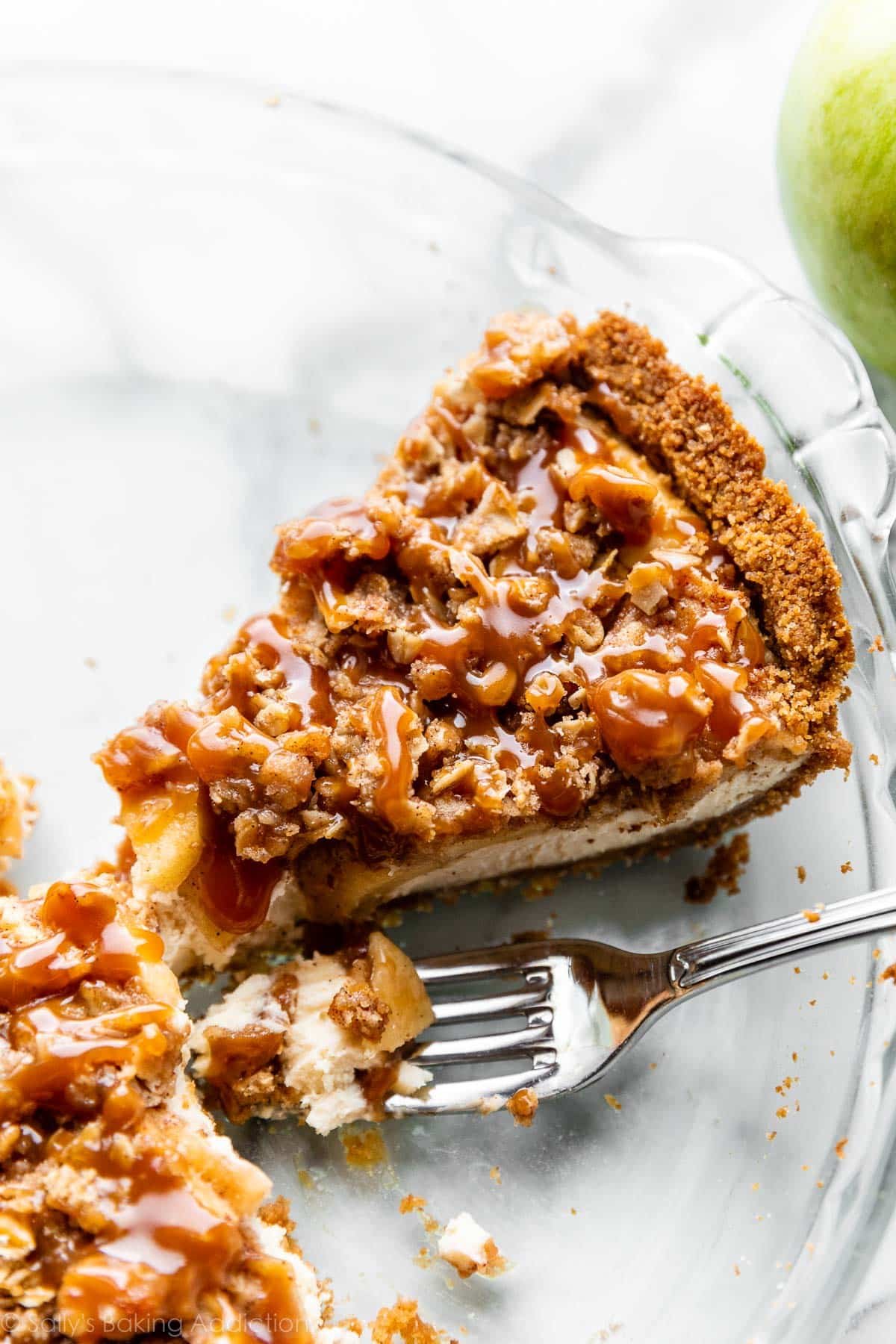 up close slice of caramel apple pie cheesecake sitting in glass pie dish.