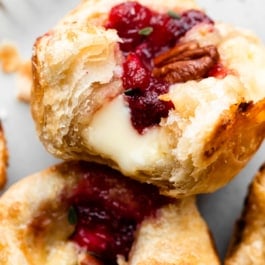 cranberry sauce and brie in a flaky puff pastry tart shown with a bite taken out.