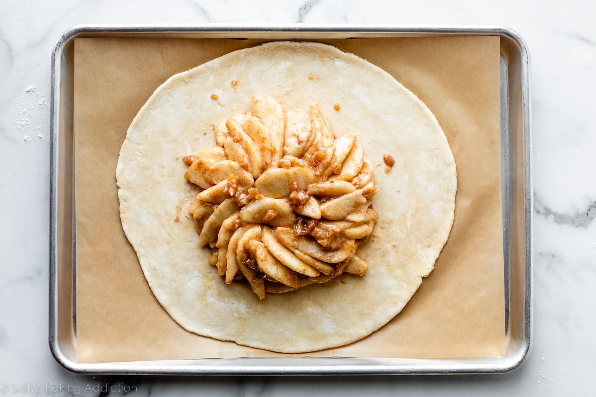 pie dough on top of lined baking sheet with pear filling arranged on top.