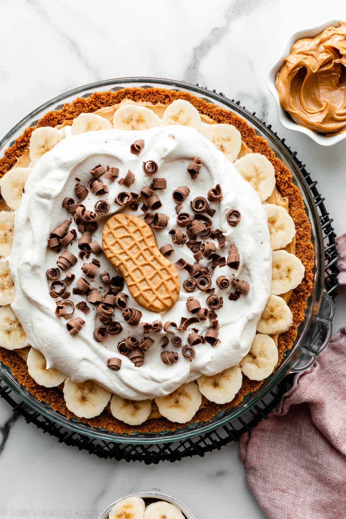 peanut butter banana cream pie with whipped cream, chocolate curls, and Nutter Butter cookie on top.