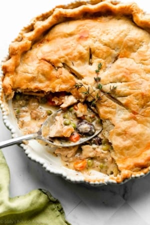 turkey pot pie with slices removed to show carrots, peas, mushrooms, turkey, and gravy filling.