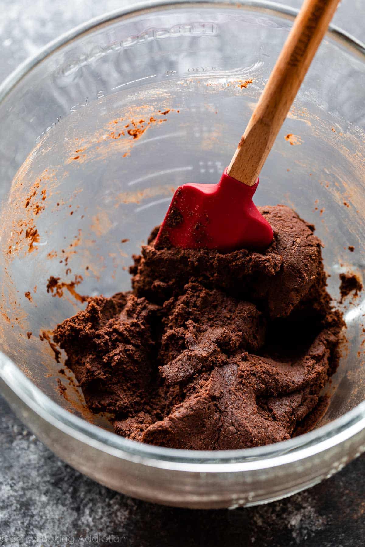 cookie dough in glass bowl with red spatula inside.