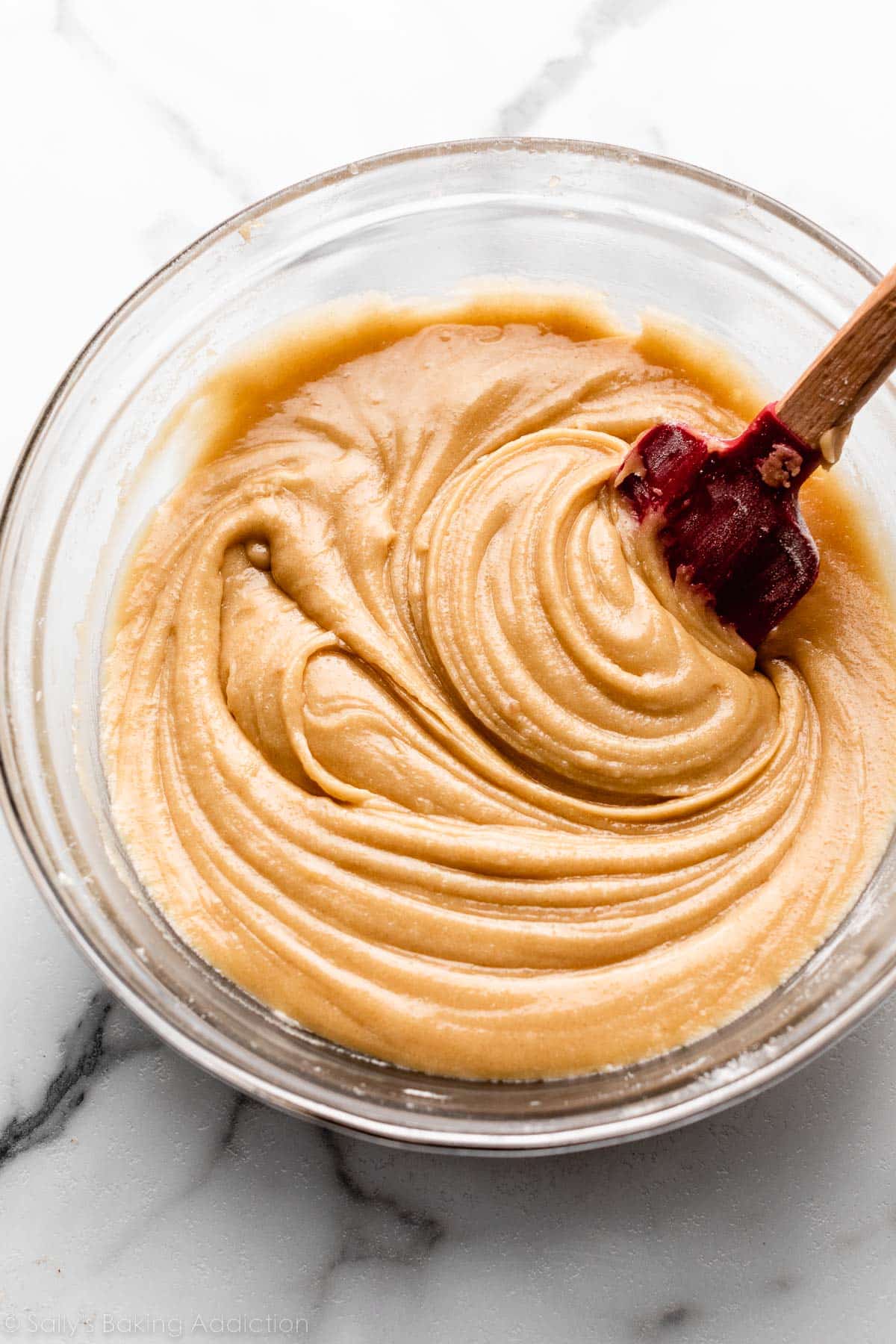 dough mixture in glass bowl with red spatula.