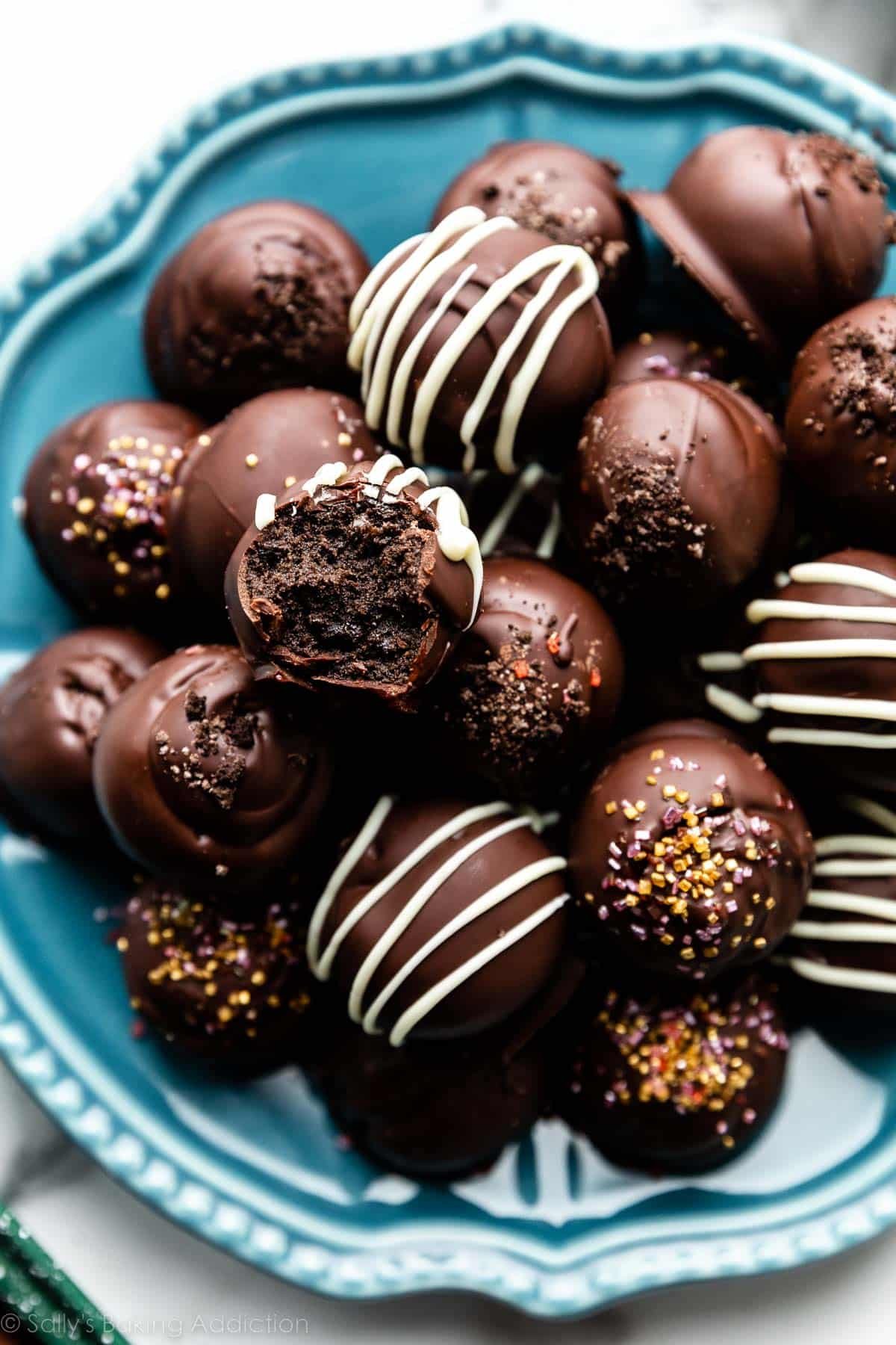 oreo balls on blue plate with some drizzled with white chocolate and others with gold sprinkles.