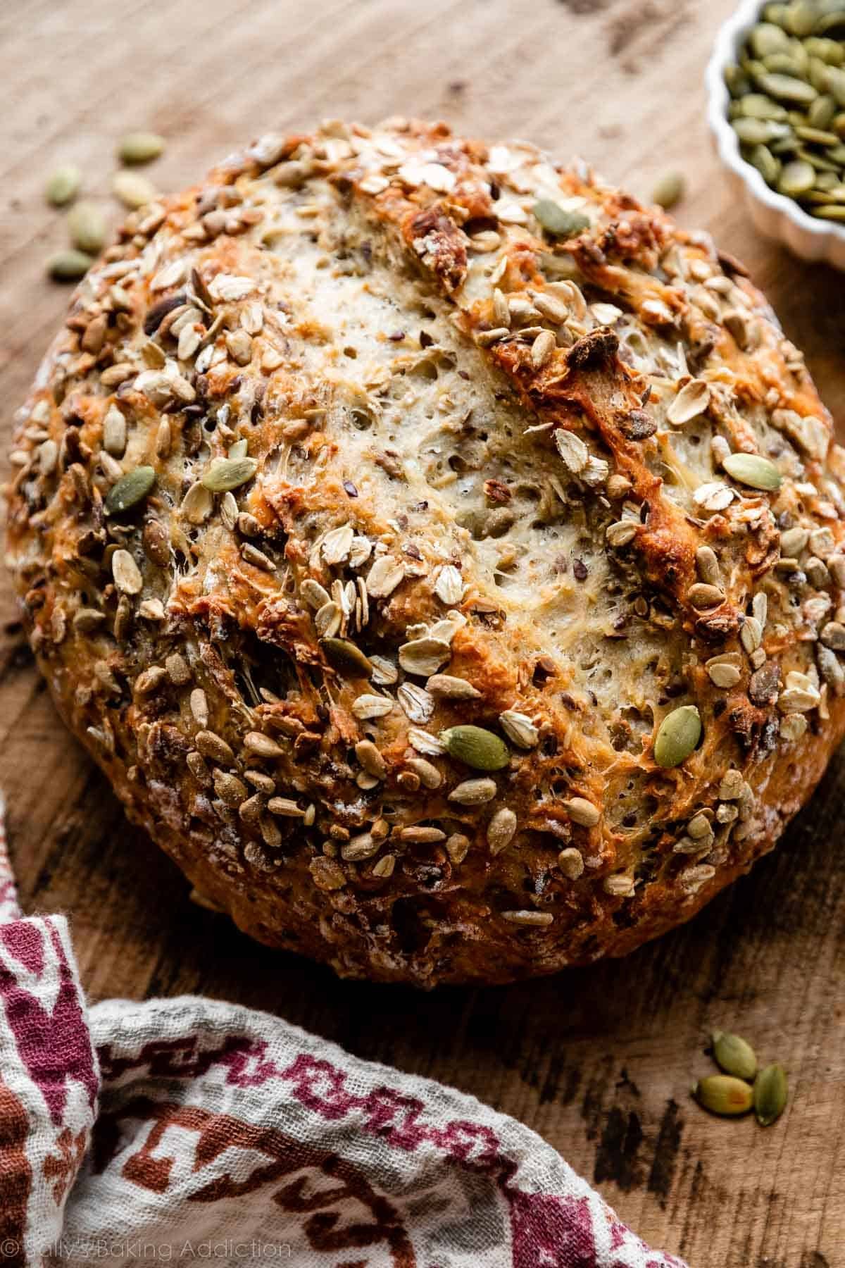 round boule of seeded bread on wooden cutting board.