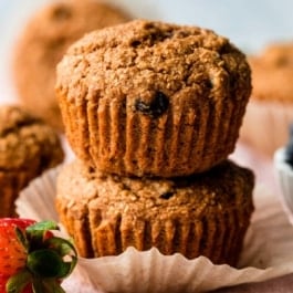 stack of two bran muffins sitting on pink linen.