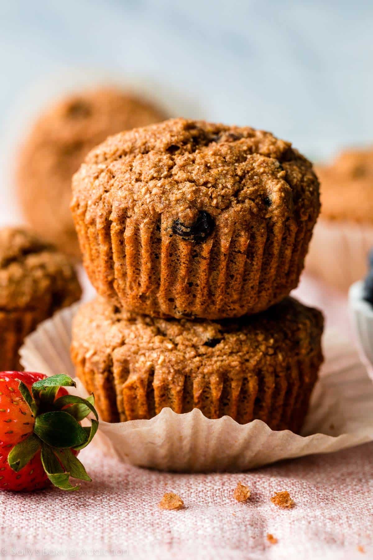 stack of two bran muffins sitting on pink linen.