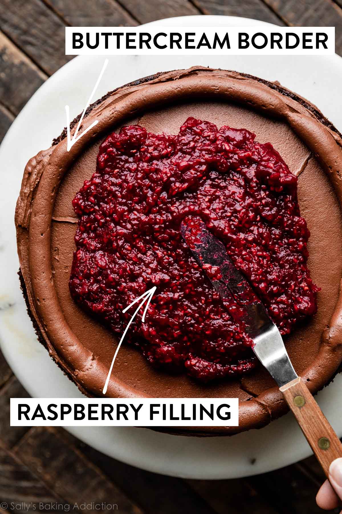 raspberry filling being spread on cake layer topped with chocolate buttercream.