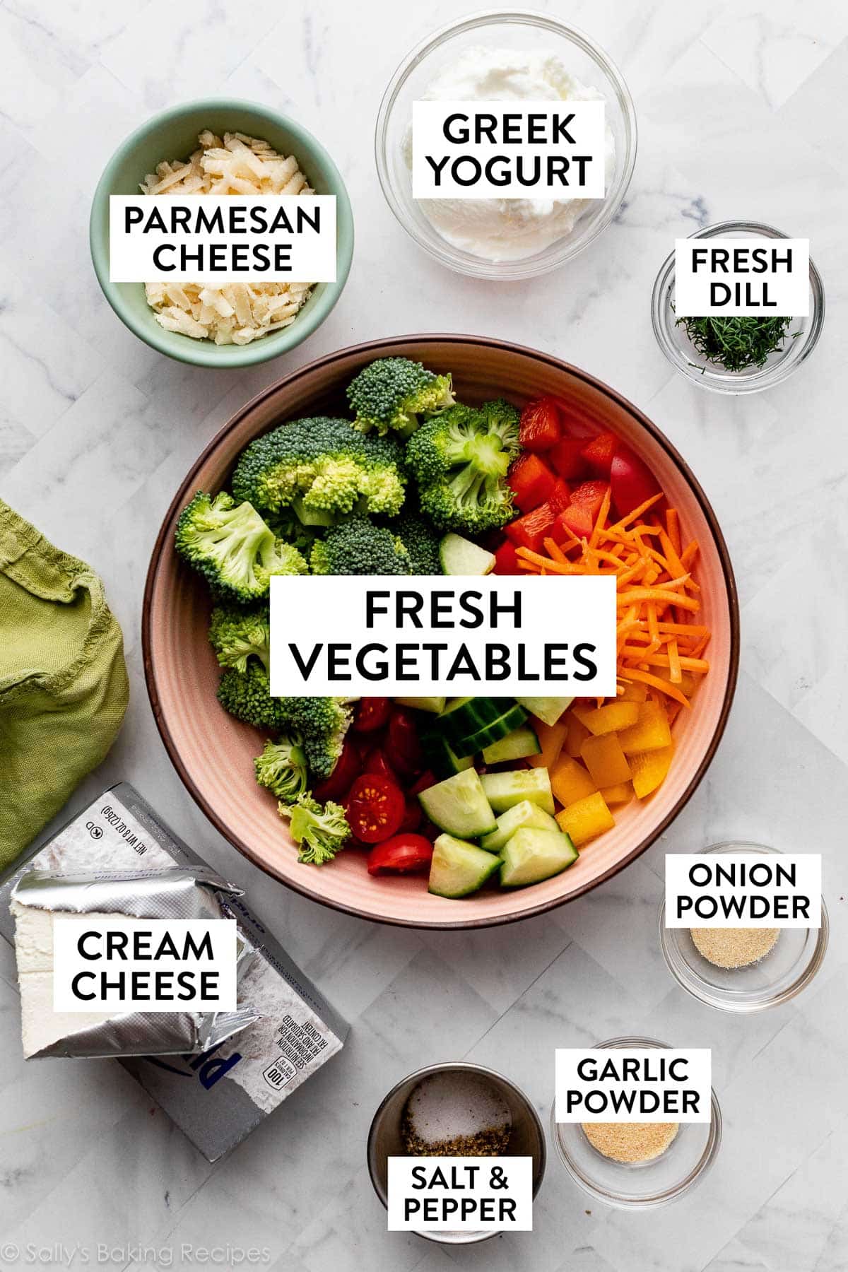 broccoli and fresh vegetables in pink bowl with other ingredients surrounding it including cream cheese, Greek yogurt, parmesan cheese, and salt and pepper.