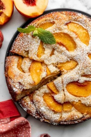 peach cake cut into slices sitting on bottom of springform pan.