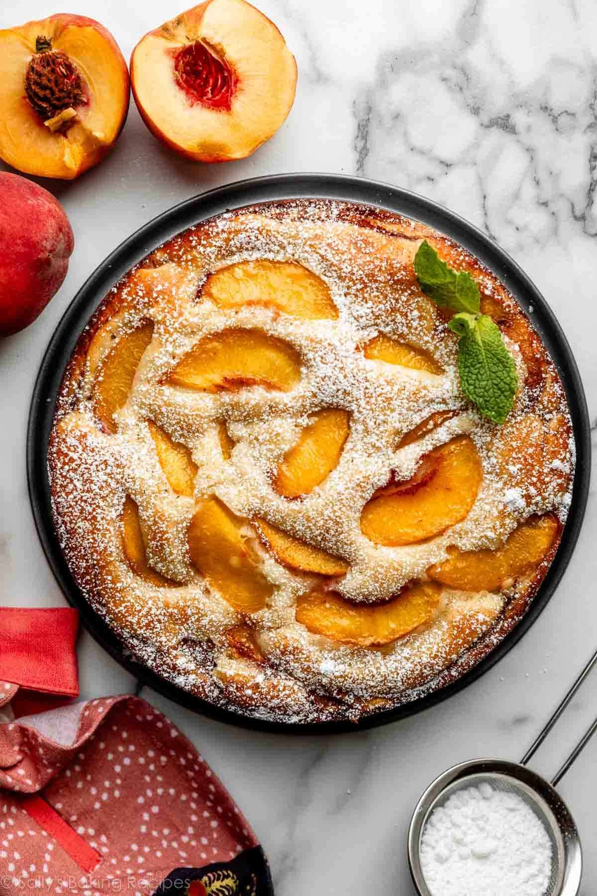 overhead view of fresh peach cake with peach slices baked in right on top and fresh mint leaves for garnish.