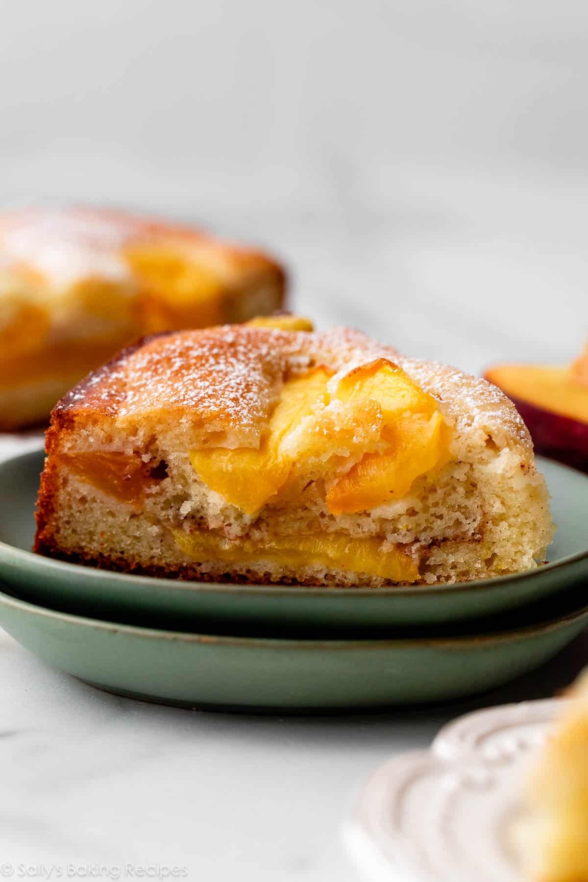 slice of peach cake on stacked green plate.