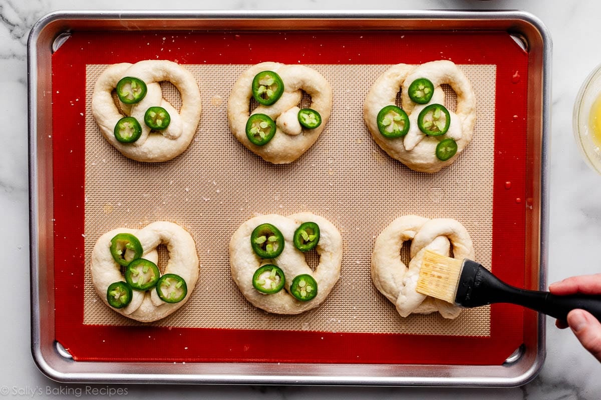 brushing melted butter on soft pretzel dough.