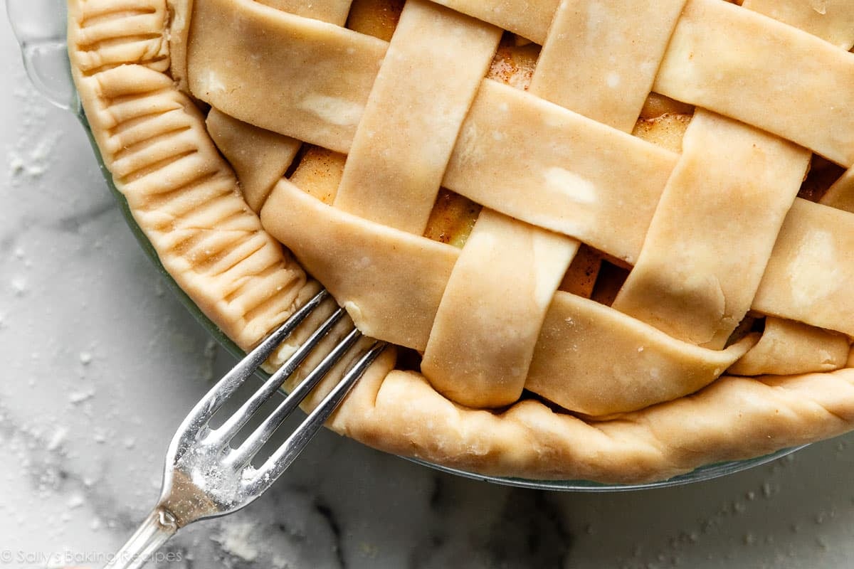 fork crimping the edges of lattice pie crust.