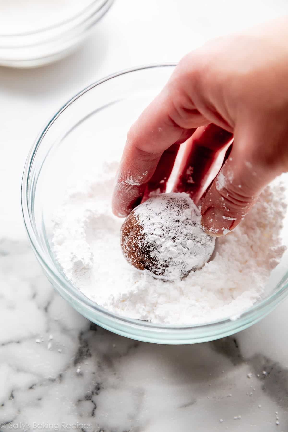 coating a cookie dough ball with confectioners' sugar.