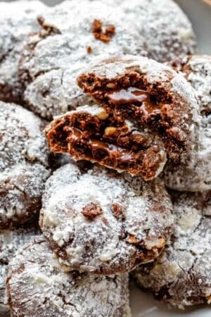 Nutella crinkles on white plate with 1 cookie broken in half to show Nutella in the center.