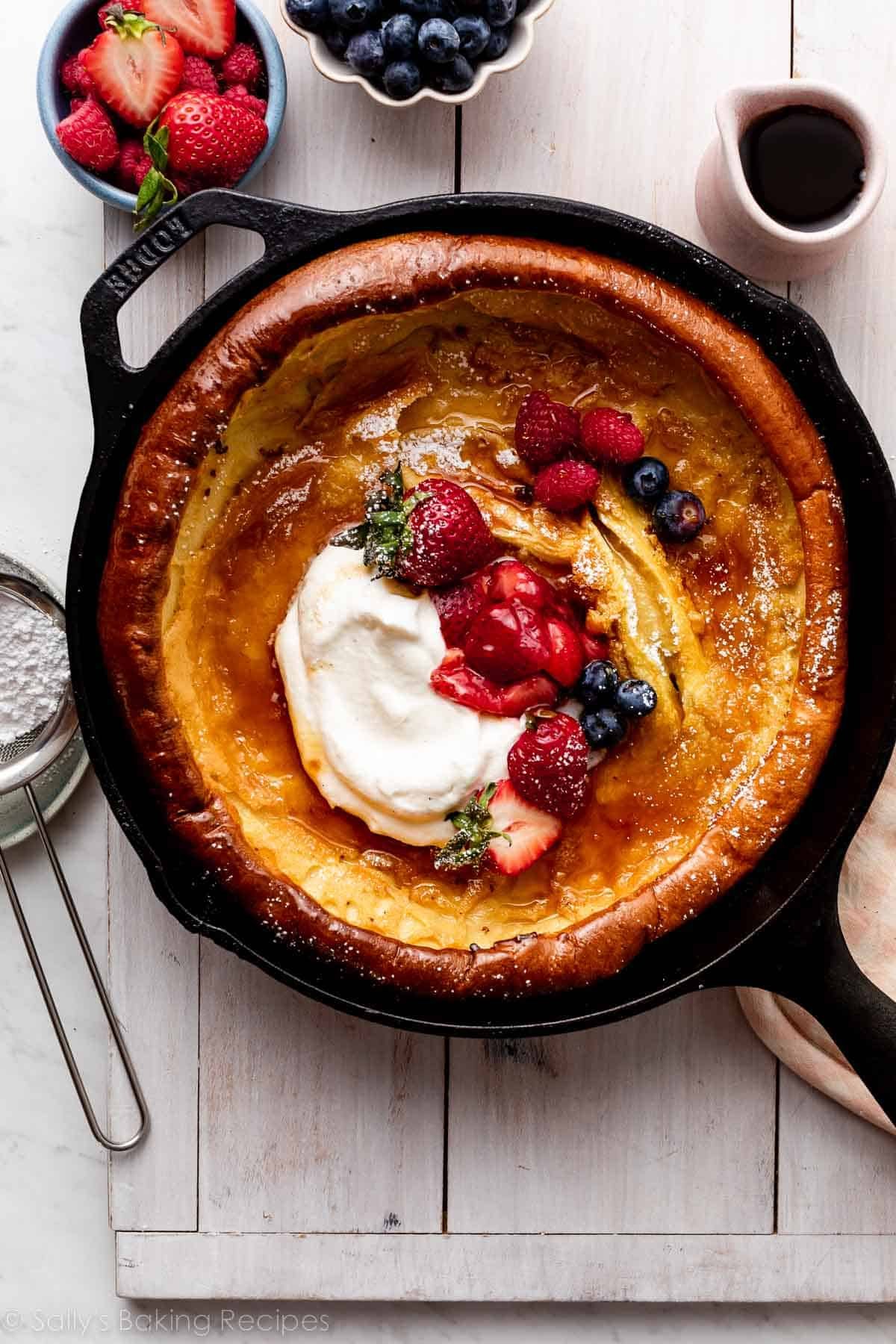 dutch baby with strawberry sauce, fresh berries, and whipped cream.