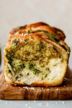 pesto pull apart bread on wooden cutting board.