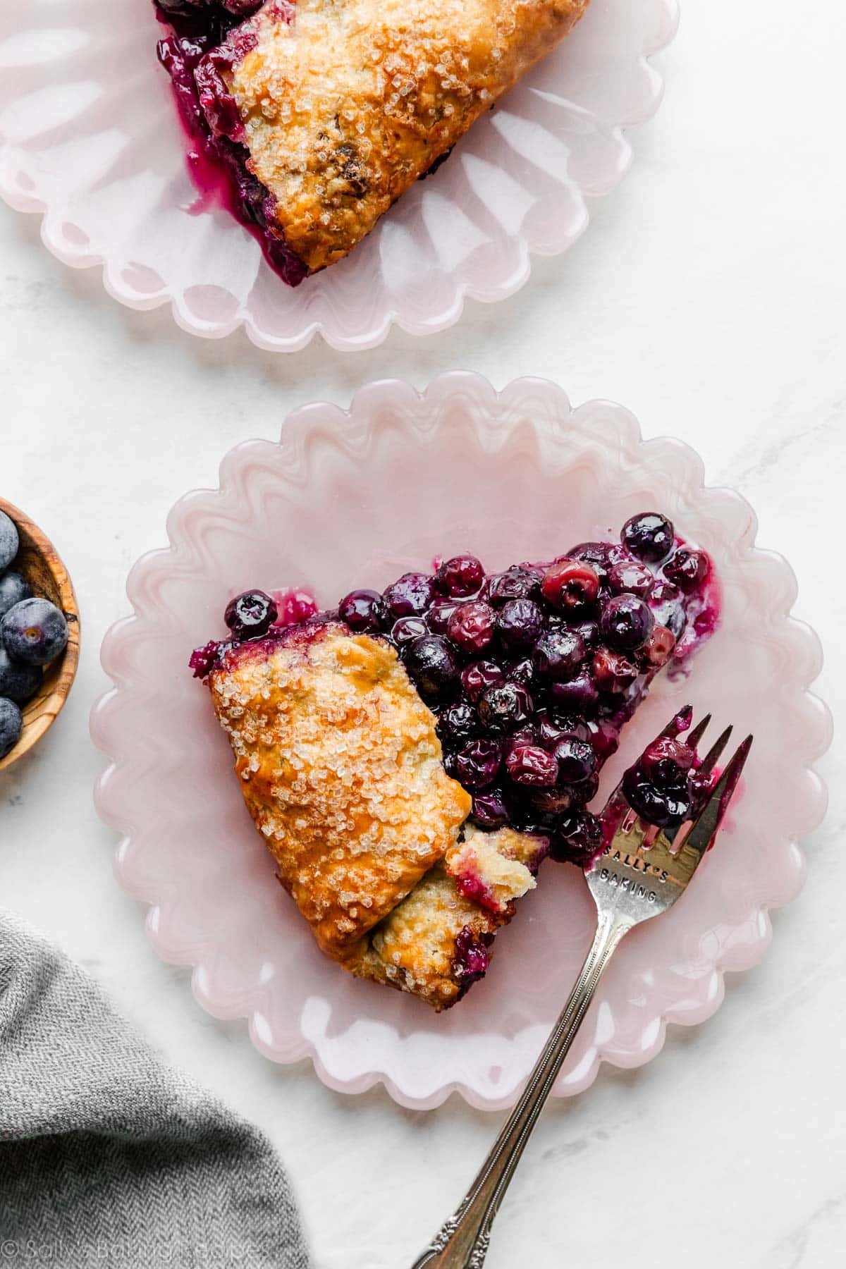 blueberry galette with buttermilk cornmeal dough sliced on pink plate.