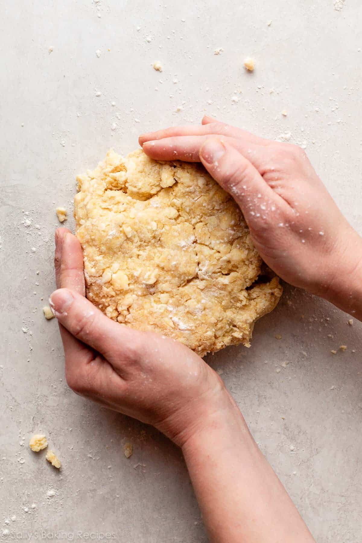 hands bringing together butter cornmeal pie dough.