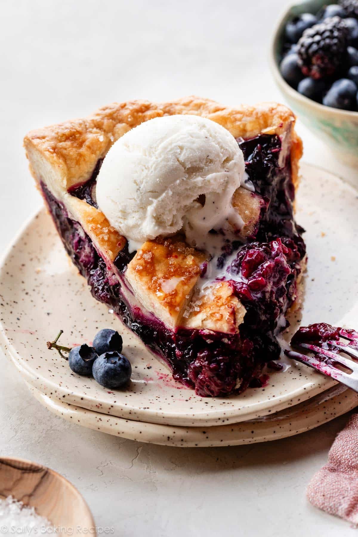 slice of triple berry pie with vanilla ice cream melting on top.