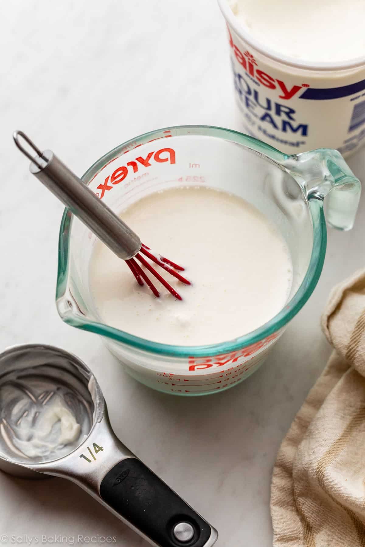 sour cream and milk mixed together in liquid measuring cup.