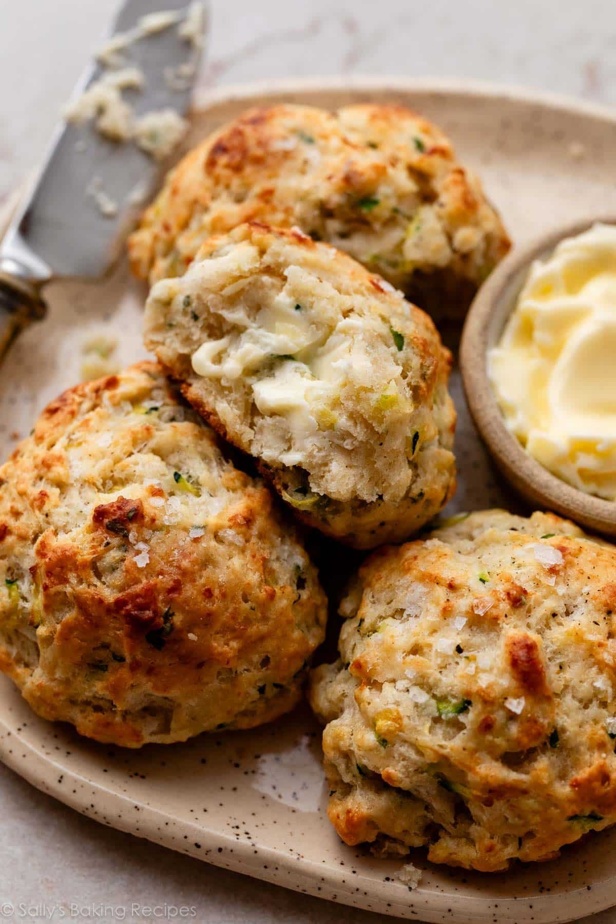 close-up of zucchini parmesan herb biscuits with butter on one.