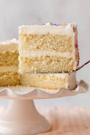 slice of white cake being taken away from cake stand.