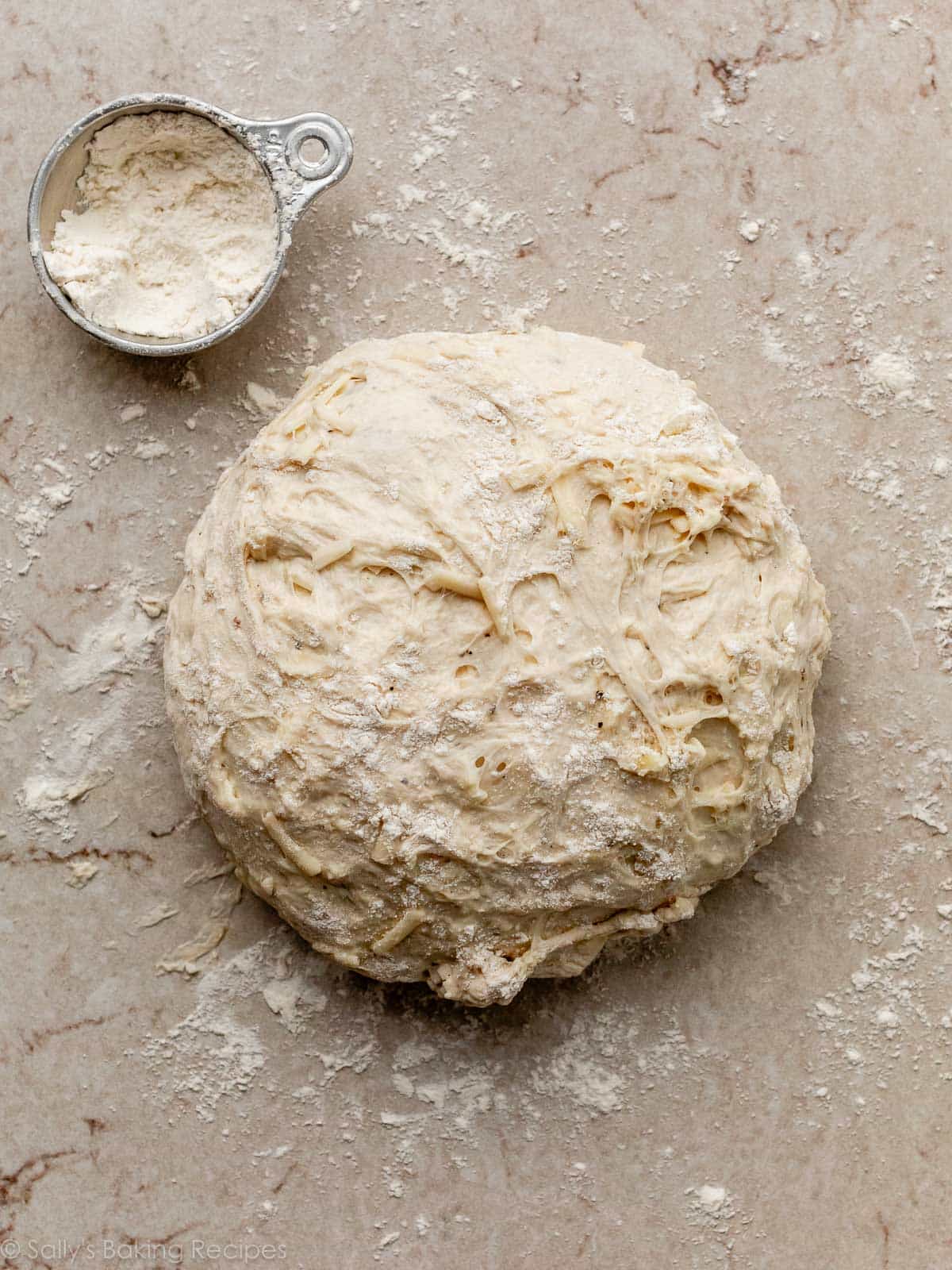 round dough on floured marble counter surface.